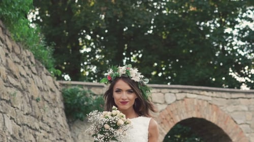 Happy Bride In Wreath Posing With Wedding Bouquet Near Castle
