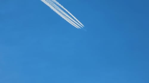 Airplane With Contrail Flying in Clear Blue Sky