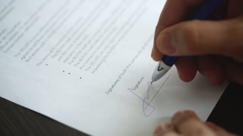 Homme d'affaires signe un contrat sur une table en bois