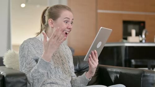 Woman Celebrates Success While Using Tablet Indoors