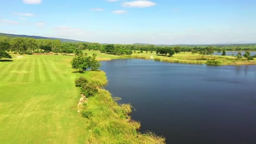 4K Aerial view of golf course with green lawn fairway and trees in summer sunny day