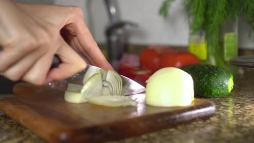 Close-Up of Hands Slicing Onion in Kitchen