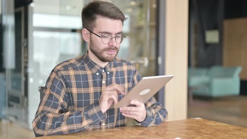 Hardworking Young Designer Using Tablet in Modern Office