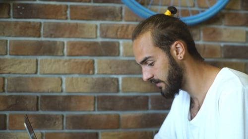 Jeune homme d'affaires tout en travaillant sur un ordinateur portable, pigiste masculin au café