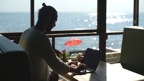 Junger Freelancer arbeitet auf dem Hintergrund des Meeres