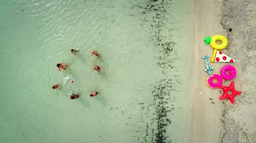 Aerial view of family playing volleyball standing in sea by sandy beach.