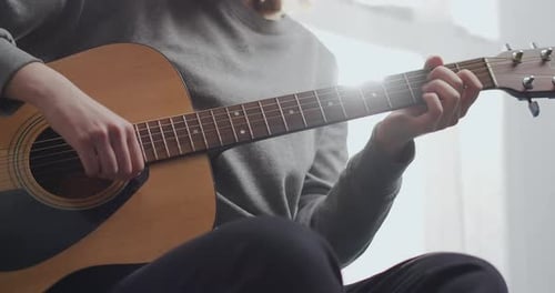 Person Playing Guitar at Home During Daytime