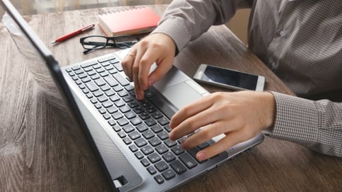 Man Typing on Laptop, Using Mobile Phone