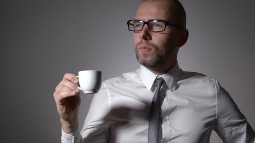 Man with Glasses Drinking Coffee from White Cup