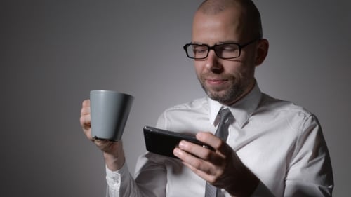 Eleganter Geschäftsmann im weißen Hemd hält eine Tasse Kaffee oder Tee in den Händen