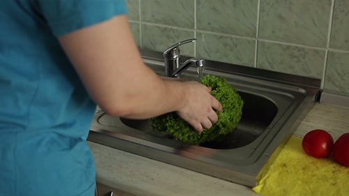 Man Washing Vegetables In The Kitchen