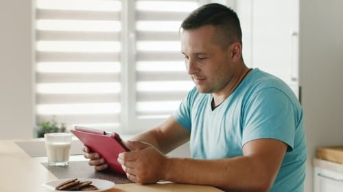 Man Browsing Tablet with Milk and Cookies