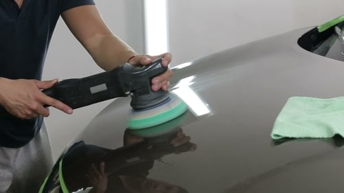 Man Polishing Car Hood in Auto Detailing Workplace