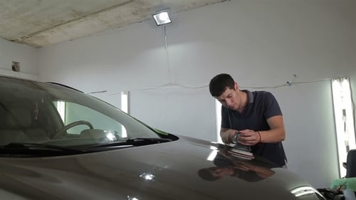 Man Buffing the Hood of a Car in Garage