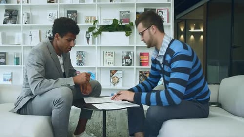 Two Businessmen Discussing and Signing a Contract