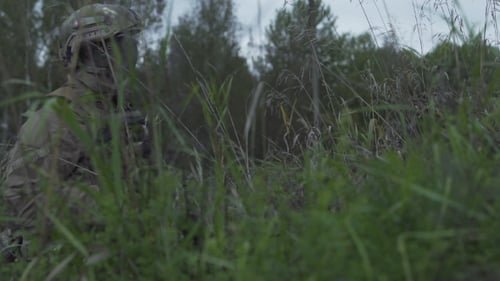 Soldiers Sitting In Wait In The Grass. Military In Arms Over The Hill