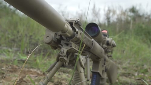 El
rifle de francotirador de camuflaje está en el suelo en la hierba. Pistolas Airsoft