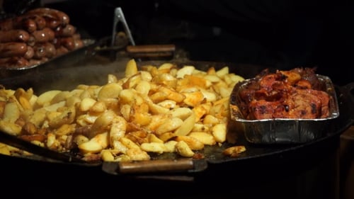 Frying Potatoes on Large Griddle with Cooked Meats