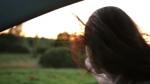 Woman Enjoys Sunset Car Ride Through Countryside
