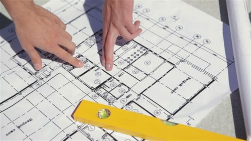 Male Fingers Point At The Plan Of The Building Construction