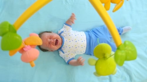Little Cute Baby Boy Lying In Crib With Toy