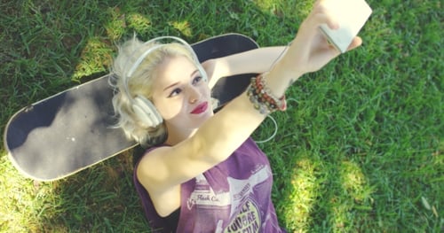 Woman on Skateboard Taking Selfie in Sunny Park