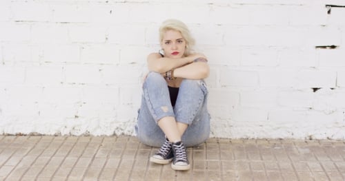 Introvert Young Woman Sitting On Paving Thinking