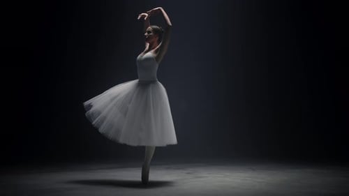 Elegant Ballerina Dancing Gracefully in Dark Studio
