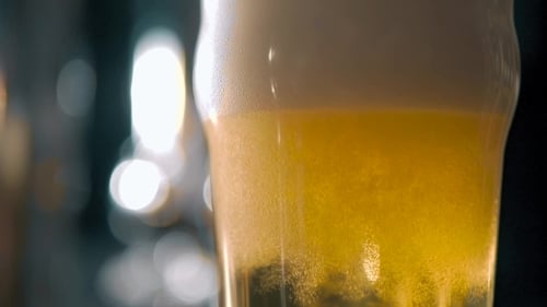 Pouring Cold Beer into Glass with Frothy Head