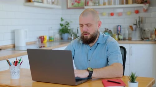 Man Working on Laptop in Bright Kitchen