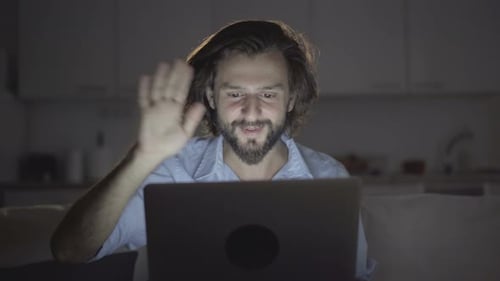 Man Smiling, Waving During Video Call on Laptop