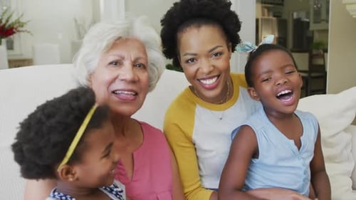 Portrait of happy african american grandmother with adult daughter and granddaughters in living room