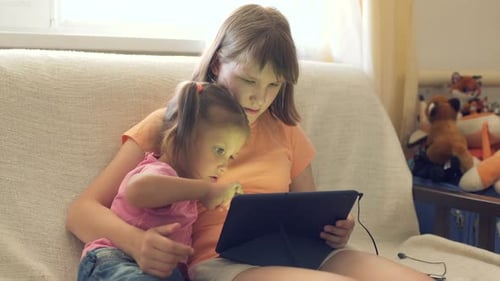 Two Girls with Tablet on Couch at Home