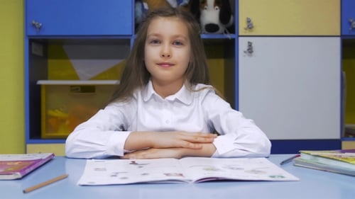 Cute Little Girl Studying At The Library Doing Homework And Smiling
