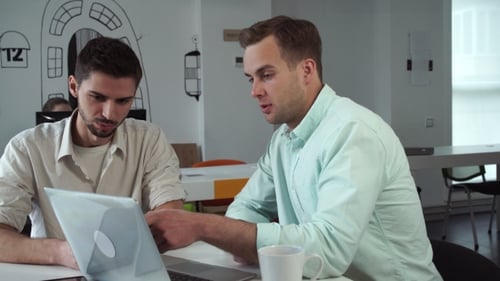 Two Men Collaborating on Laptop in Modern Office