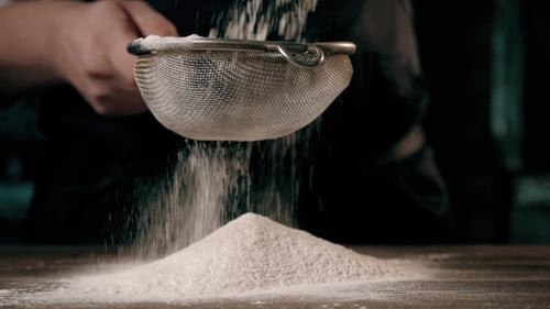 Sifting Flour onto Pile on Wooden Table