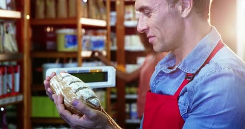 Smiling staff holding bread in supermarket