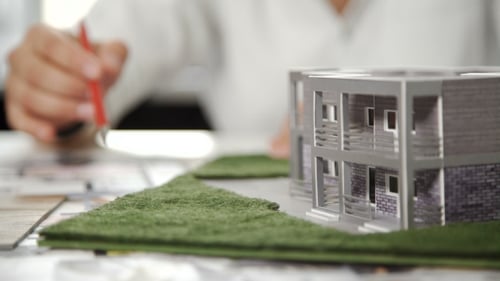 Architect Reviewing Building Design with Blueprint and Model