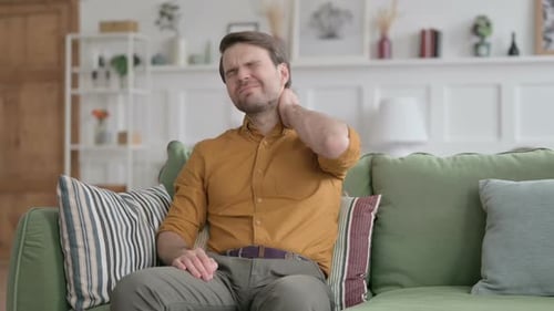 Man on Couch Rubbing Aching Neck
