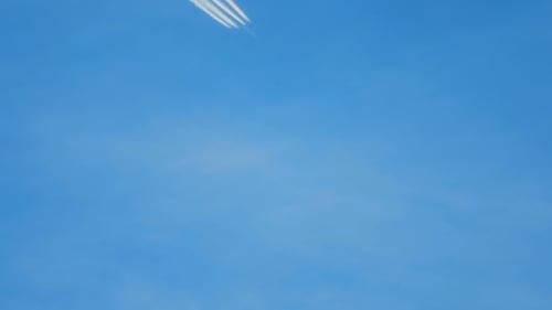 Airplane with Contrail Flying Across a Blue Sky