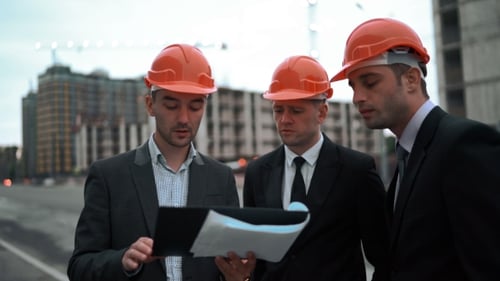 Young Architects With Blueprint Discussing Sketch Of New Building Construction