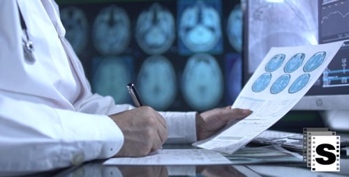 Doctor Reviews Data and Writes Notes in Hospital