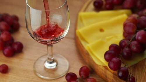 Red Wine Being Poured Into Glass With Cheese