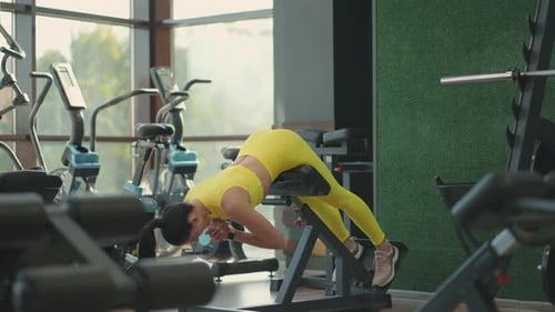 Young Beautiful Hispanic Woman Performs Hyperextension in the Gym