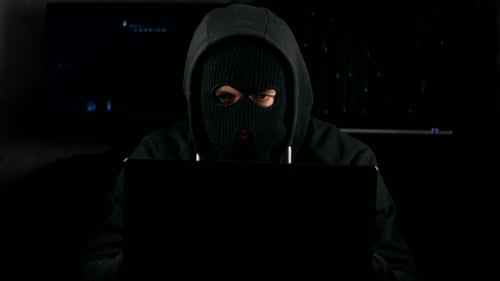 Dangerous Hacker In a Mask Working On a Computer In a Dark Office Room
