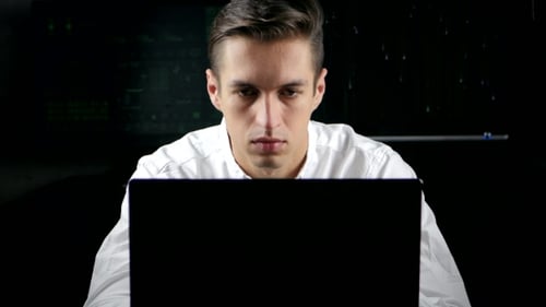 Geschäftsmann arbeitet an einem Computer in einem dunklen Büroraum