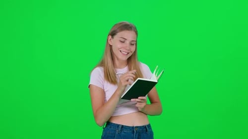 Woman Thinking and Writing in Notebook on Green Screen