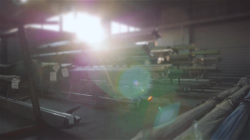 Tubos de acero se amontonan en el estante en el almacén. Stock moderno en puesta de sol, bengalas