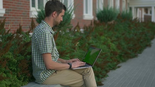 Man Working on Laptop with Green Screen Outdoors