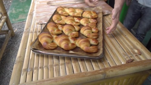 Fresh Croissants on Baking Sheet on Bamboo Table